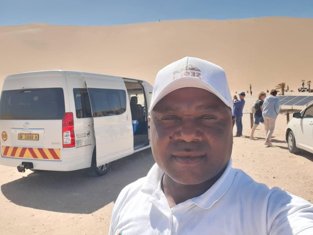 SEGEN Tours owner with the branded minibus at a desert tour stop