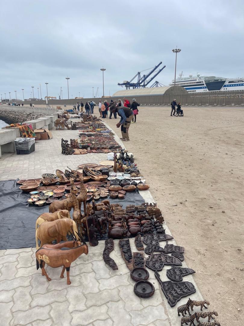 Handcrafted wooden sculptures and souvenirs at the Walvis Bay port craft market with cruise ship in background