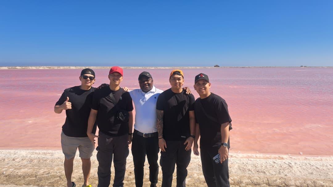 Happy tourists posing for a group photo with the stunning pink lake backdrop