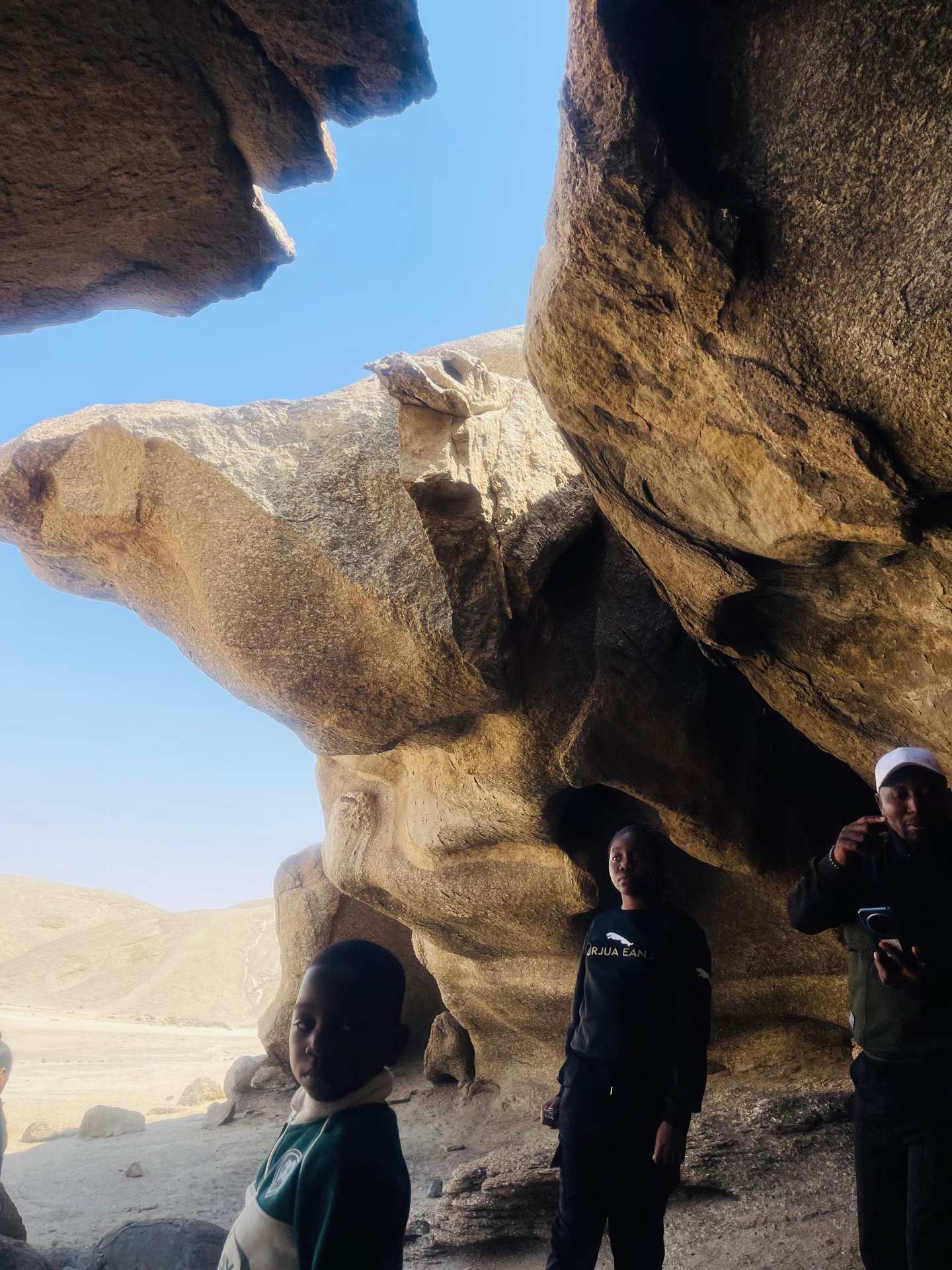 Group of visitors standing under a natural rock arch formation in the Namibian wilderness