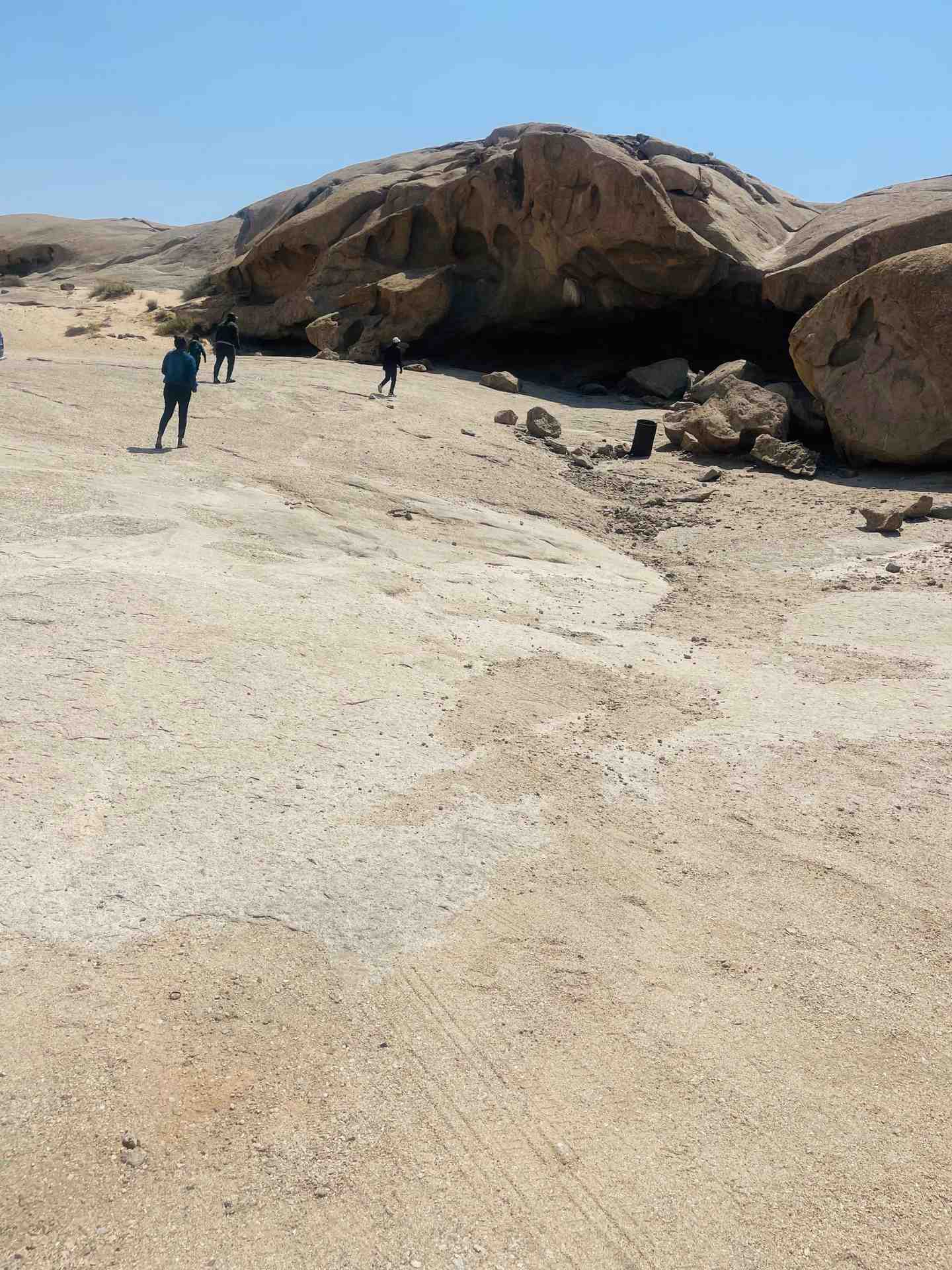 Tourists exploring a massive rock cave formation in the Namibian desert landscape