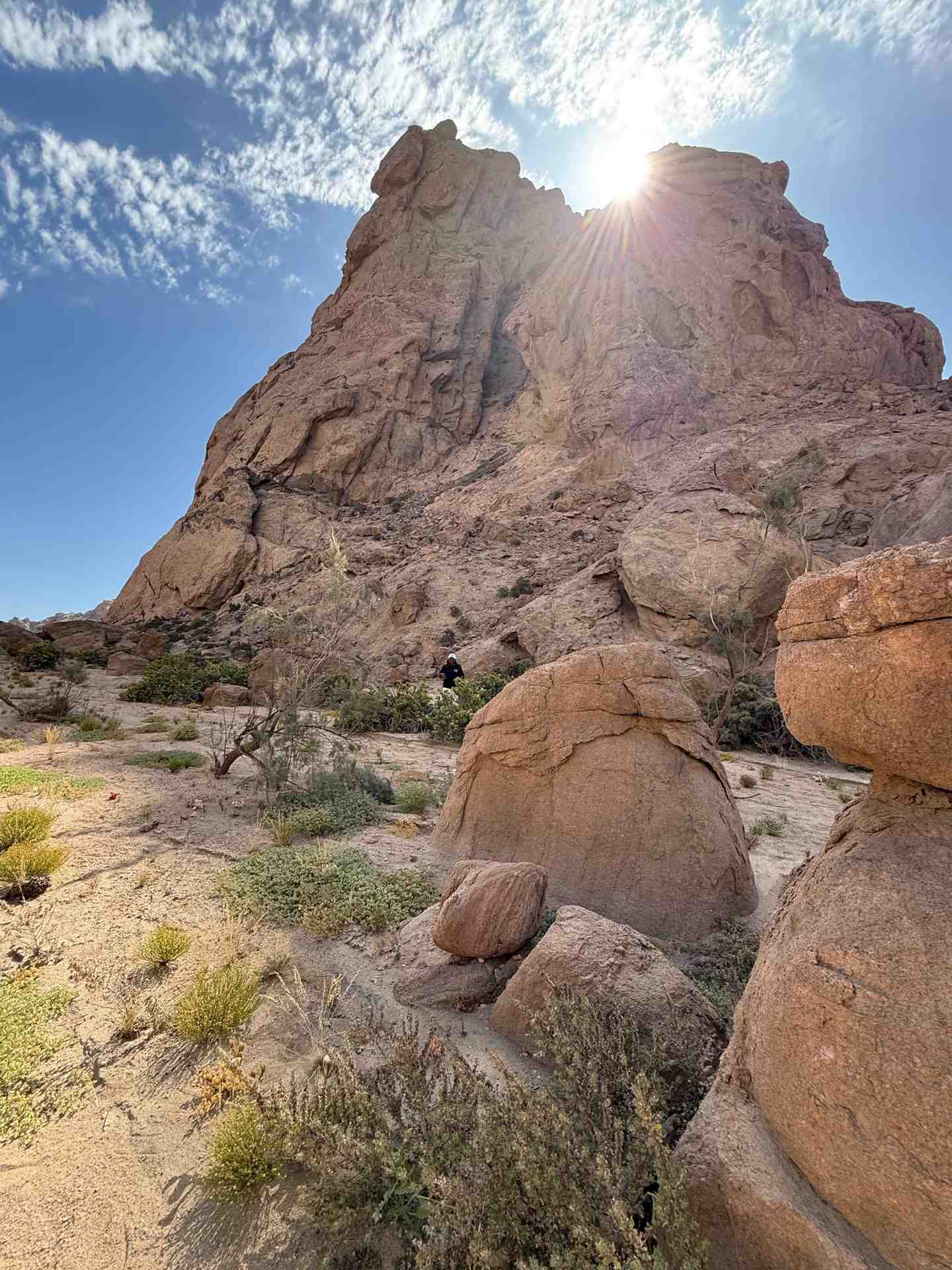 Majestic Spitzkoppe granite peak with sun flare and scattered boulders in foreground